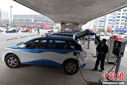 资料图：电动汽车在充电桩旁充电。中新社记者 武俊杰 摄