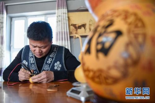 在新疆霍尔果斯市加尔苏村，村民曹光耀在自己的工作室内创作葫芦烙画（2月6日摄）。新华社记者 丁磊 摄