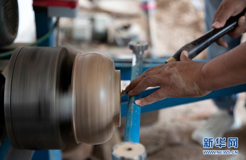 阿里木·乌斯曼用机床制作木碗，待木碗雏形制造完毕就会进入雕刻阶段。新华网 茹斯坦摄