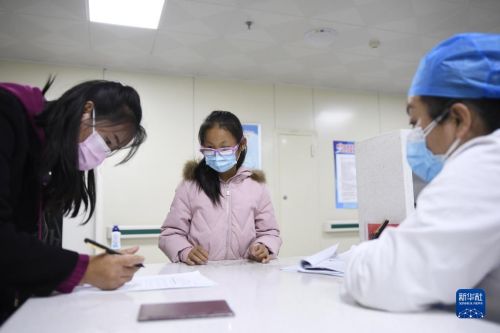 10月29日，在甘肃省永靖县，学生在家长的陪护下在接种点填写疫苗接种信息。新华社发（史有东 摄）