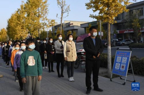 10月29日，在甘肃省永靖县，学生在家长的陪护下等候接种疫苗。新华社发（史有东 摄）