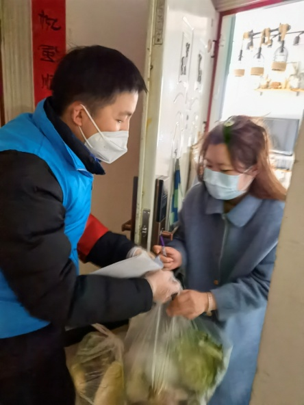 图为西北信息报下沉一线人员把菜送到住户手里